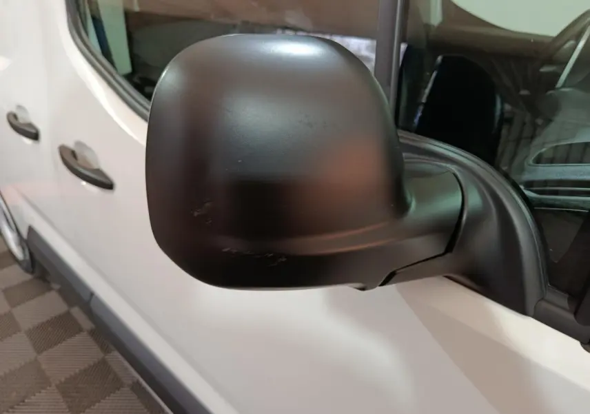 Gros plan sur le rétroviseur noir côté gauche d’un Citroën Berlingo blanc, vue latérale avant.