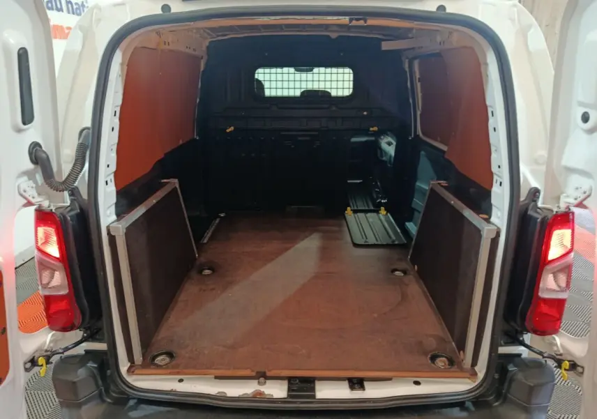 Vue arrière ouverte du Citroën Berlingo blanc montrant l'espace de chargement avec cloison pleine noire.