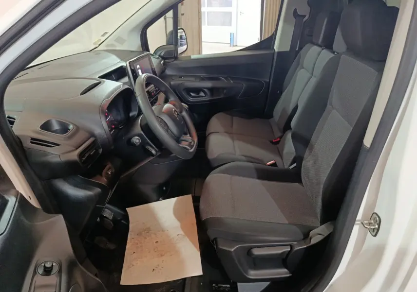 Intérieur du Citroën Berlingo blanc 2021, vue côté conducteur montrant tableau de bord et sièges tissu gris.