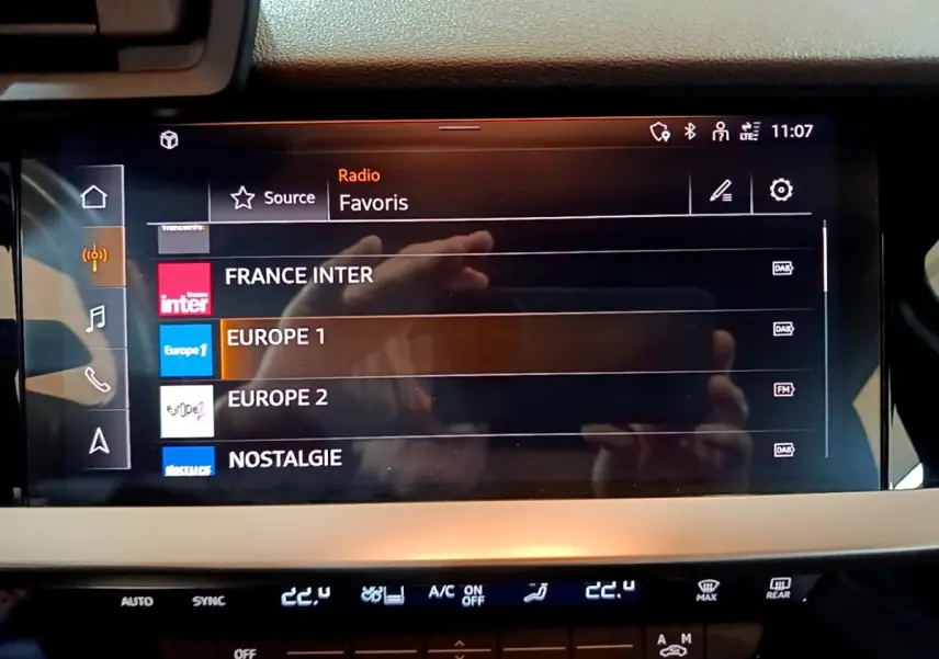 Écran tactile central de l’Audi A3 gris foncé, affichant les stations radio favorites avec interface moderne.