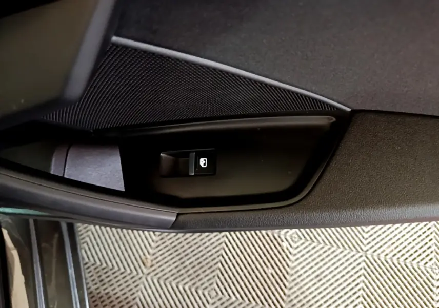 Gros plan sur le bouton de verrouillage des portes côté conducteur de l'Audi A3 gris foncé, intérieur.