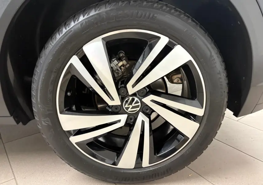 Gros plan sur la jante noire et argentée du Volkswagen T-Roc 1.5 TSI 150 DSG7 R-Line Edition 2025 en noir intense.