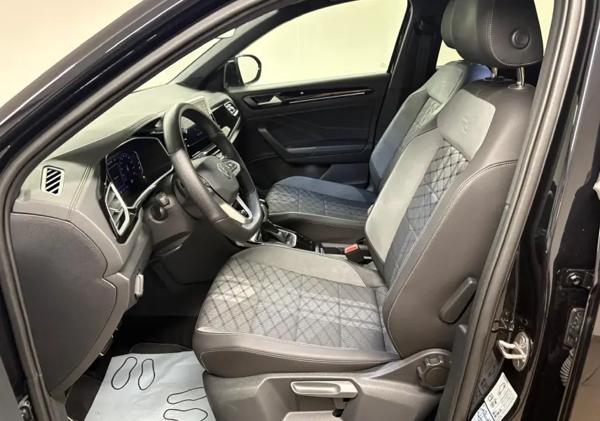 Vue intérieure côté conducteur du Volkswagen T-Roc 1.5 TSI R-Line noir intense, sièges avant en tissu et cuir avec surpiqûres.