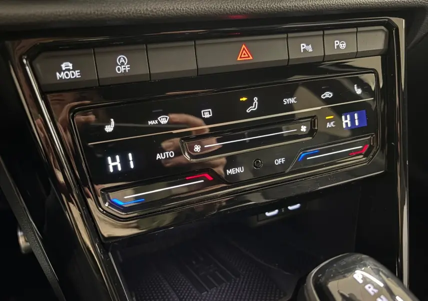 Gros plan sur la console centrale noire du Volkswagen T-Roc 2025, affichant la climatisation automatique et la boîte auto DSG7.