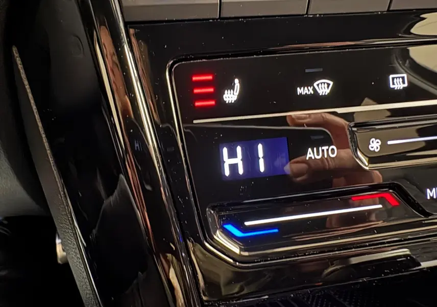Gros plan sur la commande de climatisation chauffante du Volkswagen T-Roc noir intense, affichant le réglage "HI".