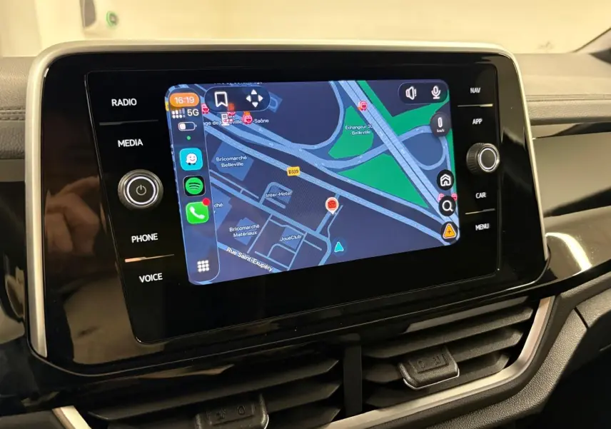 Écran tactile central du Volkswagen T-Roc 2025 affichant la navigation, entouré de commandes noires brillantes.