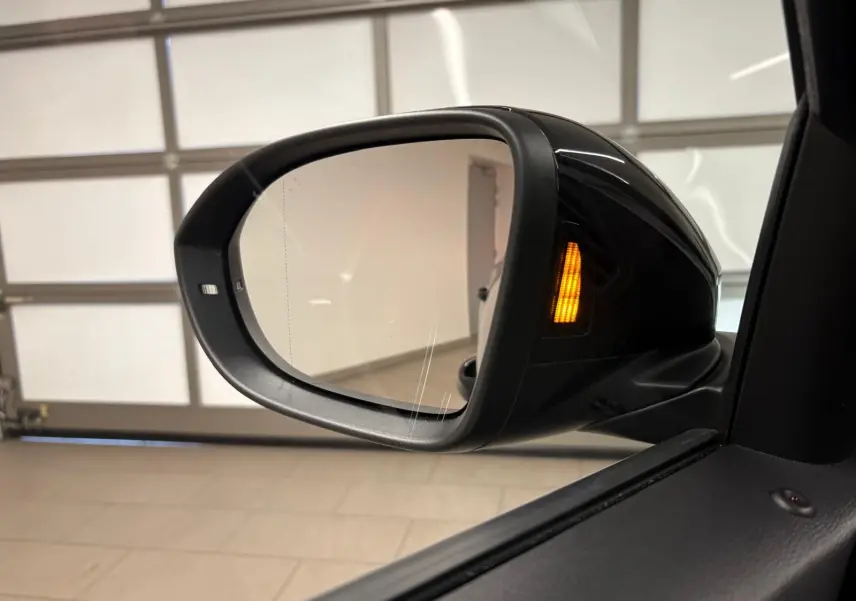 Rétroviseur droit noir intense du Volkswagen T-Roc 2025 avec clignotant orange allumé en intérieur.