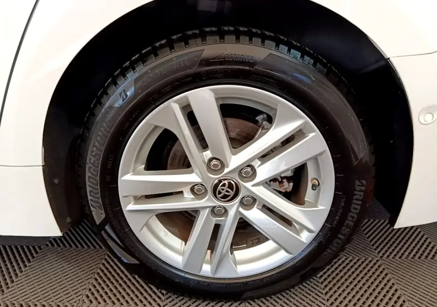 Gros plan sur la roue avant droite blanche d'une Toyota Corolla hybride 2022 avec jante alliage et logo Toyota central.