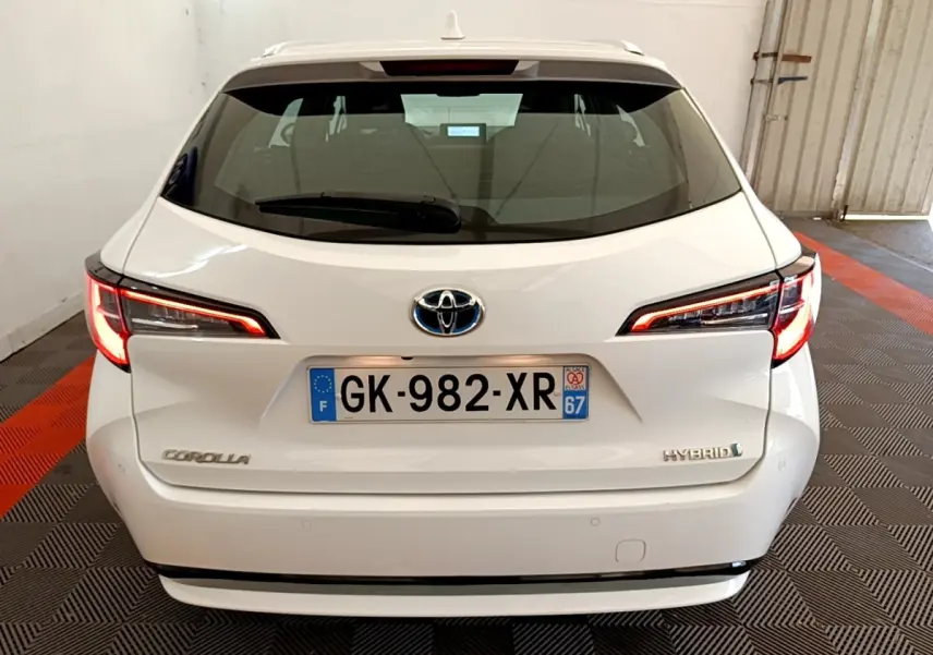 Vue arrière d'une Toyota Corolla hybride blanche 2022 avec feux LED allumés dans un garage.