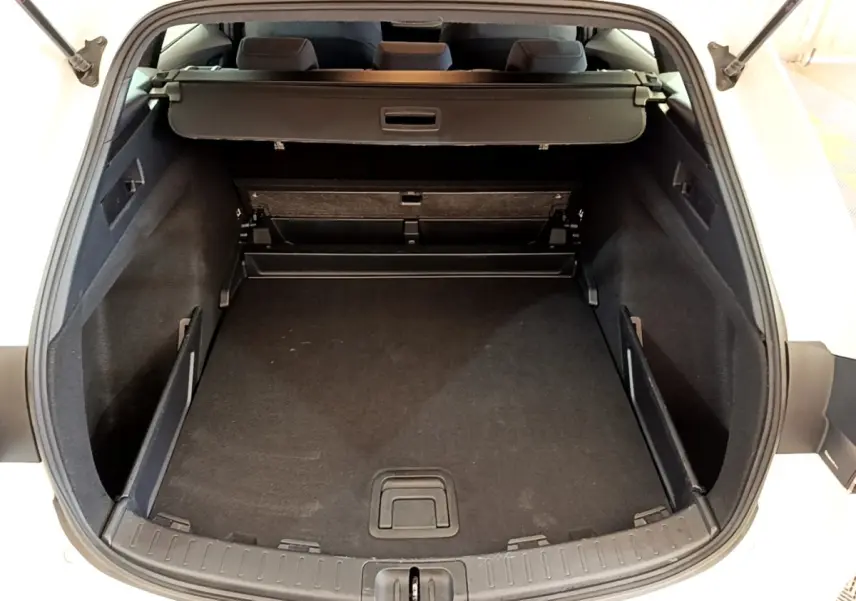 Coffre ouvert de la Toyota Corolla hybride blanche 2022, vue arrière montrant l’espace de chargement vide et la tablette cache-bagages.