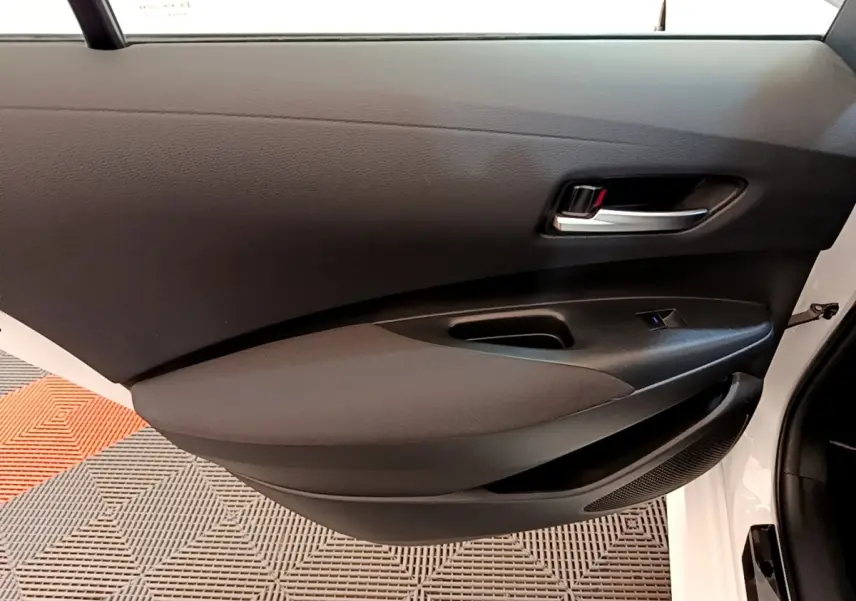 Vue intérieure du panneau de porte avant gauche noir de la Toyota Corolla Hybride blanche 2022.
