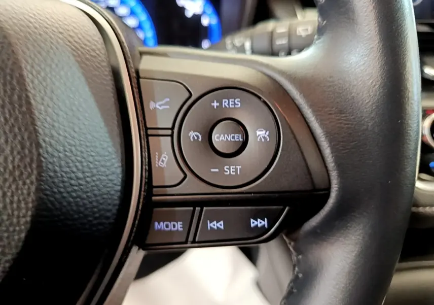 Gros plan sur les commandes multifonctions du volant cuir noir de la Toyota Corolla Hybride 2022.