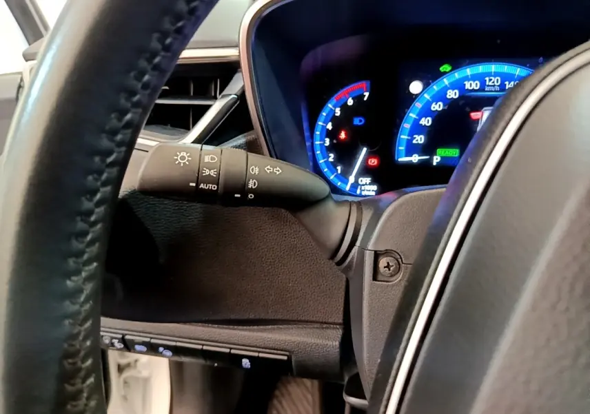 Vue rapprochée du tableau de bord et du volant cuir de la Toyota Corolla hybride 2022 avec affichage numérique bleu.