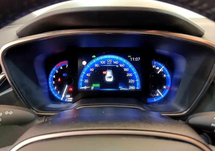 Tableau de bord numérique de Toyota Corolla Hybride 2022, affichage bleu avec compteur vitesse et indicateurs variés.