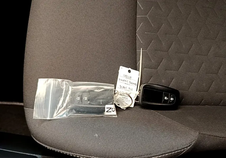 Gros plan sur la banquette arrière grise avec deux clés noires de Toyota Corolla hybride posées dessus.
