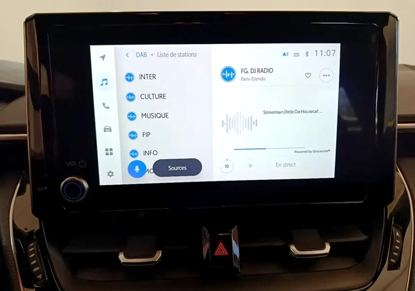 Écran tactile central 8 pouces affichant la radio numérique dans l’habitacle d’une Toyota Corolla blanche.