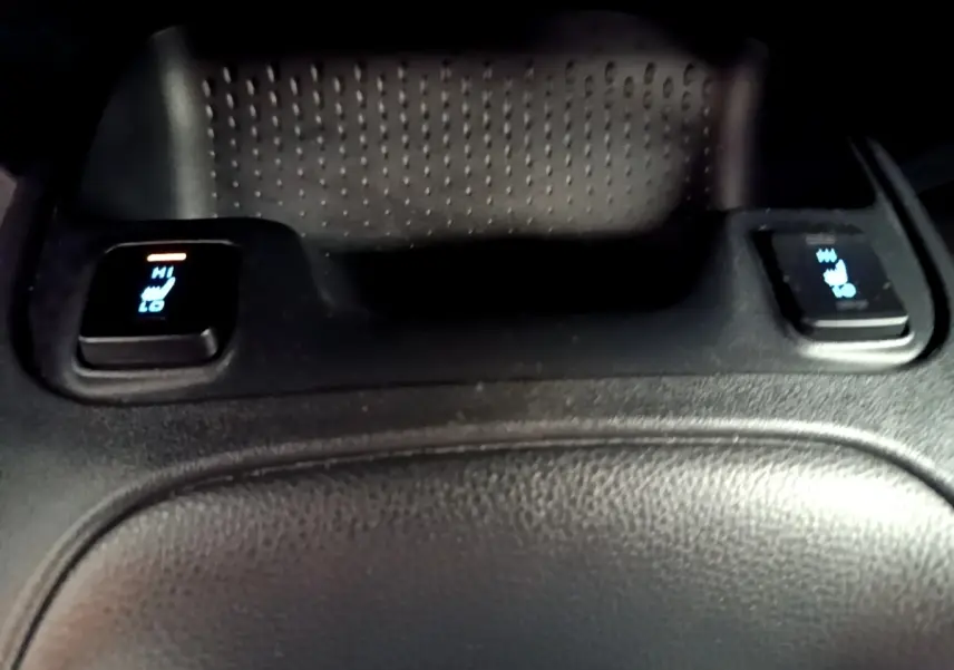 Détail des commandes de chauffage des sièges arrière sur la console centrale en cuir noir de la Toyota Corolla hybride blanche.