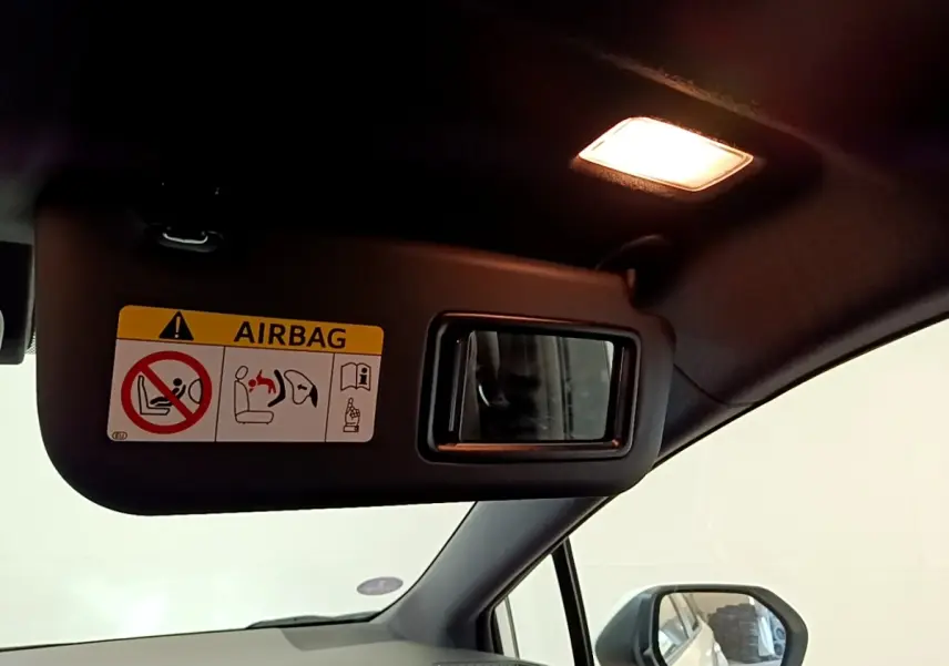Intérieur de la Toyota Corolla hybride 2022, vue côté conducteur sur pare-soleil avec miroir et avertissement airbag.