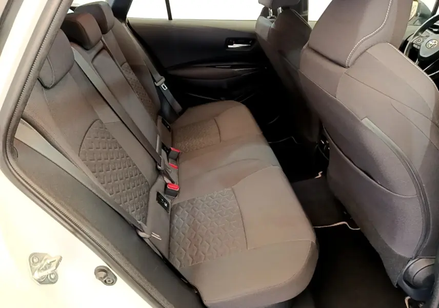 Vue intérieure côté gauche montrant la banquette arrière grise de la Toyota Corolla Hybride 2022 blanche.