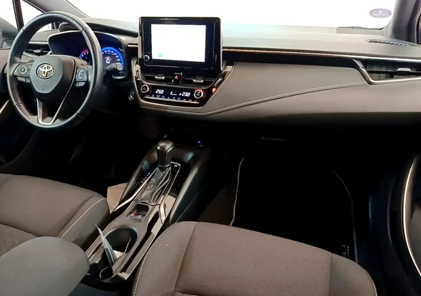 Intérieur de la Toyota Corolla Hybride 2022 vu de face, avec tableau de bord noir et écran tactile central.