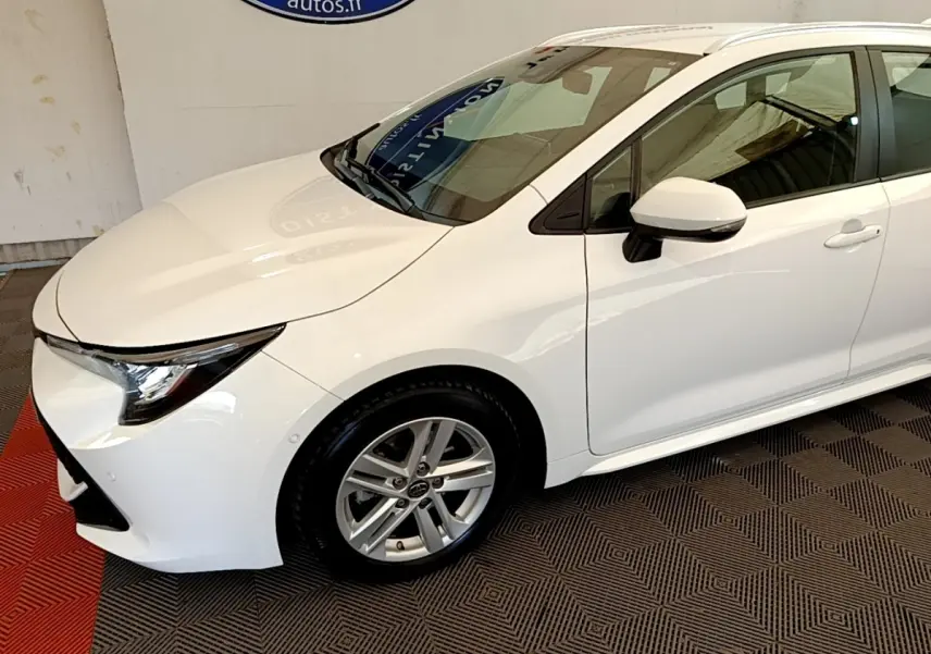 Vue 3/4 avant droite d'une Toyota Corolla hybride blanche avec jantes alliage et rétroviseurs blancs.