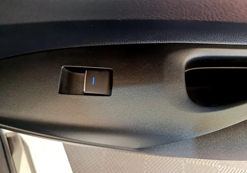 Détail du bouton de verrouillage électrique sur la porte intérieure côté conducteur de la Toyota Corolla blanche hybride 2022.