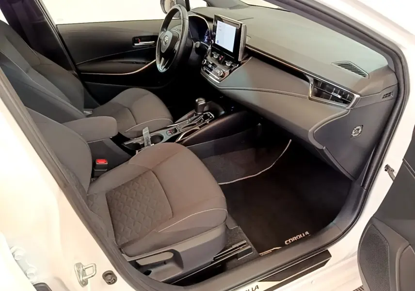 Vue intérieure côté conducteur de la Toyota Corolla blanche 2022, avec tableau de bord moderne et écran tactile central.