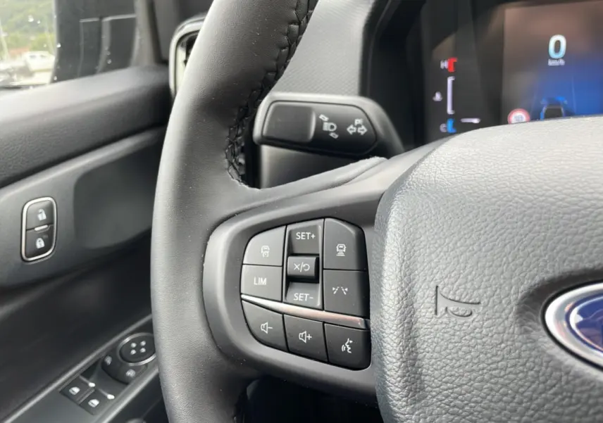 Gros plan sur le volant cuir multifonctions du Ford Ranger gris carbone, avec commandes de régulateur et audio visibles.