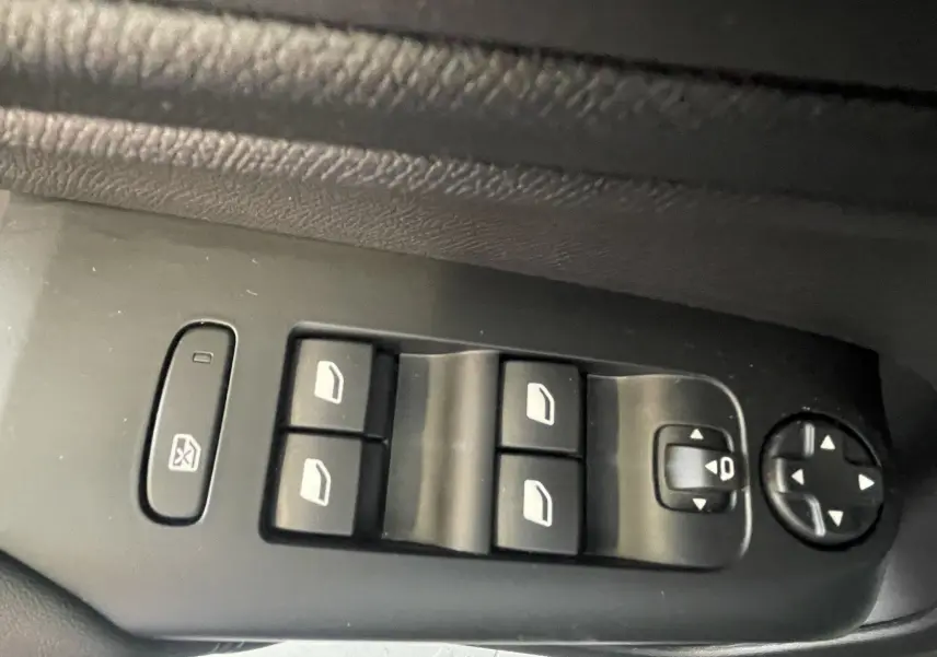 Vue rapprochée des commandes de lève-vitres et réglage des rétroviseurs sur la porte côté gauche du Citroën C5 Aircross gris platinium.