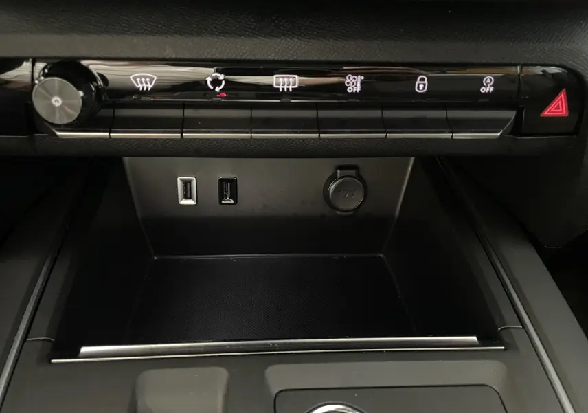 Vue rapprochée de la console centrale du Citroën C5 Aircross hybride 2025, avec ports USB, prise 12V et commandes tactiles noires.