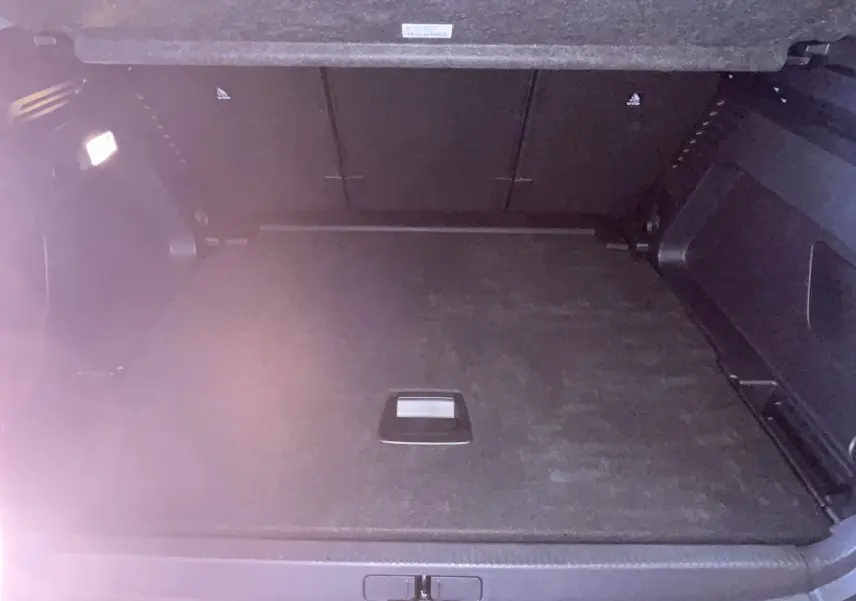 Coffre spacieux et vide du Citroën C5 Aircross hybride gris platinium, vu de l'arrière avec éclairage intérieur.