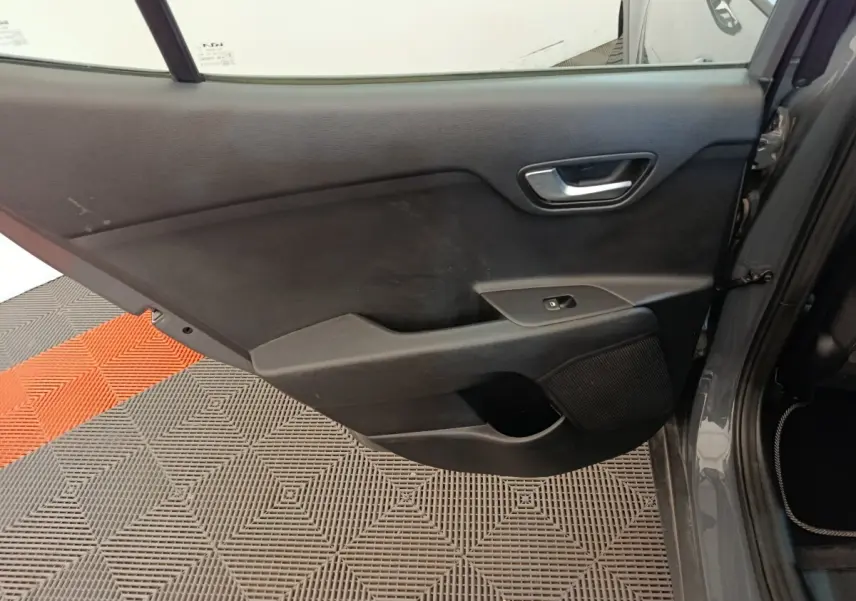 Vue intérieure de la porte arrière droite gris foncé du Kia Stonic 2023 avec poignée et commande de fenêtre.