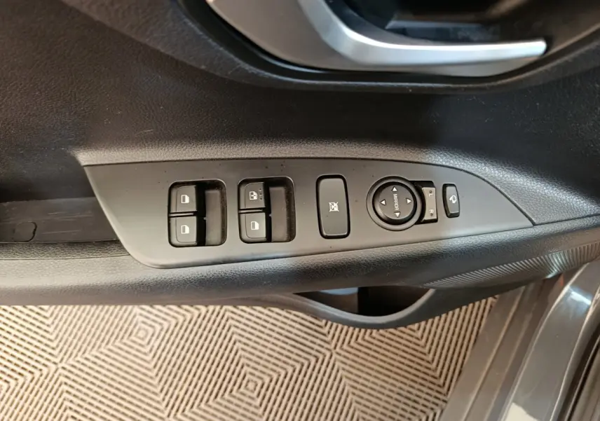Gros plan sur la commande des vitres et rétroviseurs côté conducteur du KIA Stonic gris foncé 2023.
