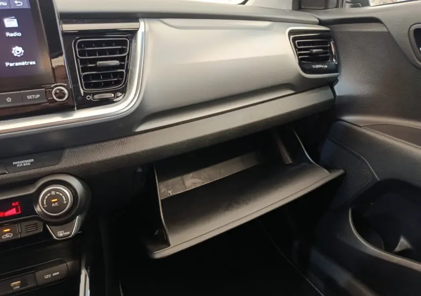 Intérieur KIA Stonic 2023 vue côté passager, tableau de bord gris clair avec boîte à gants ouverte.