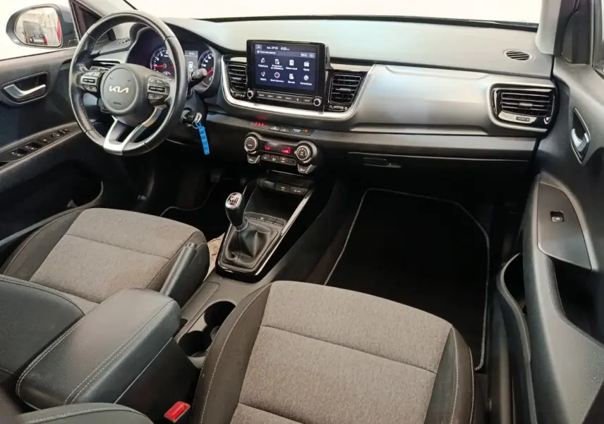 Vue intérieure côté conducteur de la Kia Stonic 2023, tableau de bord avec écran tactile et volant cuir multifonctions.