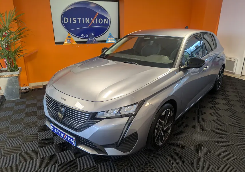 Peugeot 308 2025 gris Artense vue 3/4 avant droit avec calandre distinctive et jantes alliage noires.