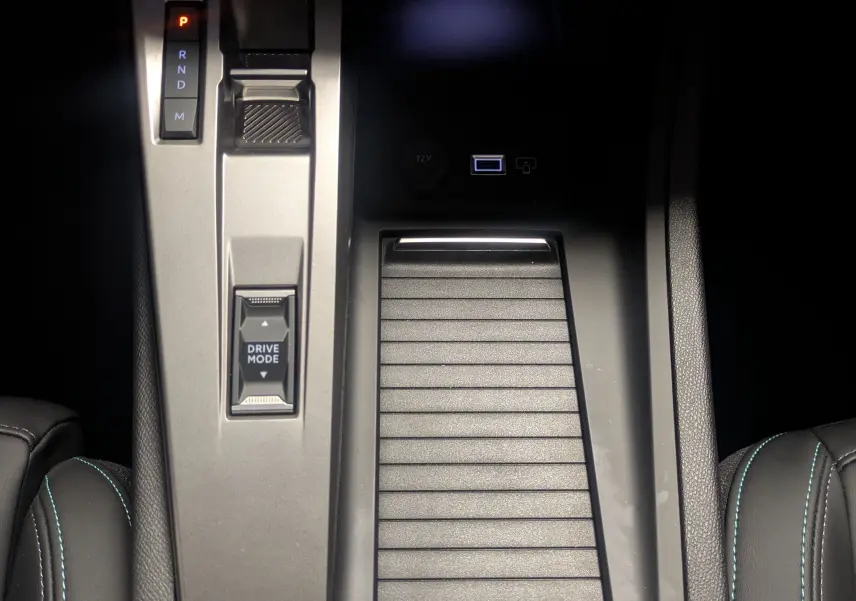 Vue plongeante sur la console centrale grise de la Peugeot 308 2025 avec boîte auto et bouton Drive Mode visible.