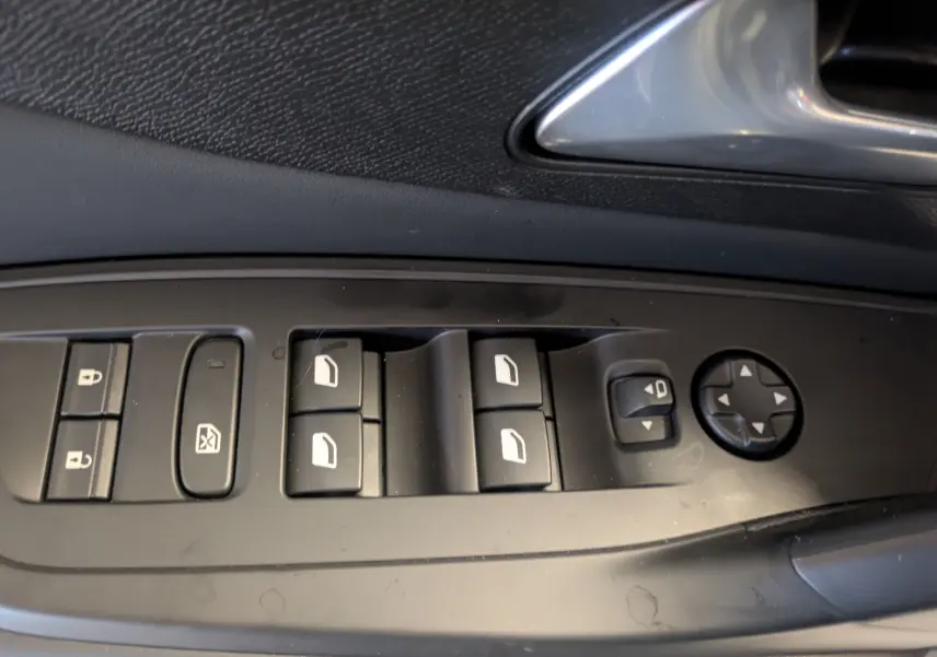 Panneau de commandes des vitres et rétroviseurs côté conducteur d'une Peugeot 308 gris Artense 2025.