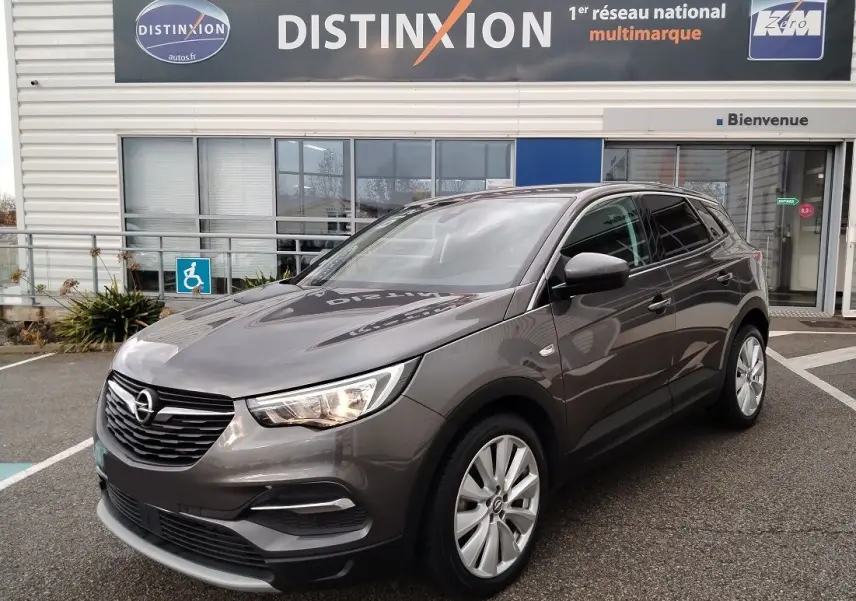 Opel Grandland X gris platinium vu en 3/4 avant droit, avec calandre noire et jantes alliage argentées.