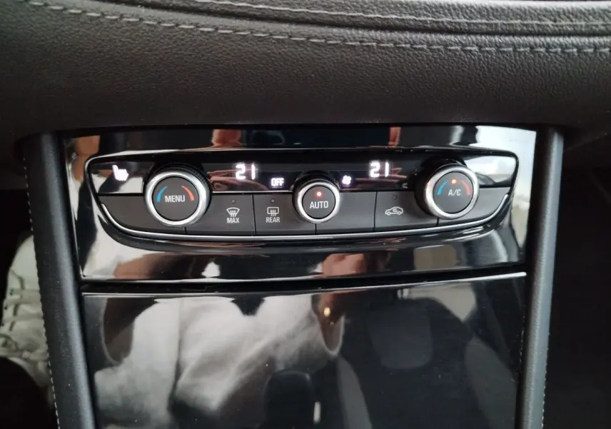 Panneau de commande de la climatisation automatique de l’Opel Grandland X 1.5 CDTI, avec affichage digital et finition noire brillante.