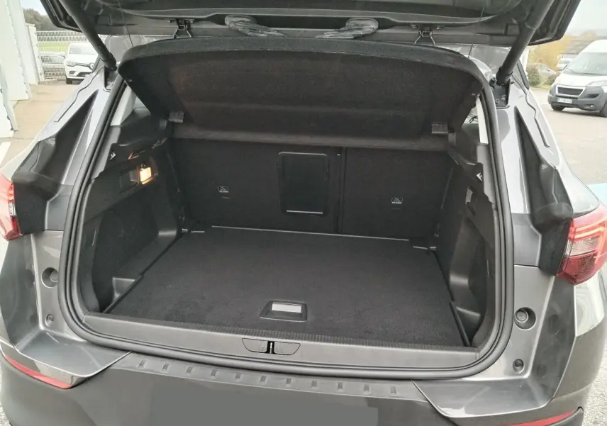 Coffre ouvert d'un Opel Grandland X gris platinium vu de l'arrière, montrant un espace de chargement propre et spacieux.