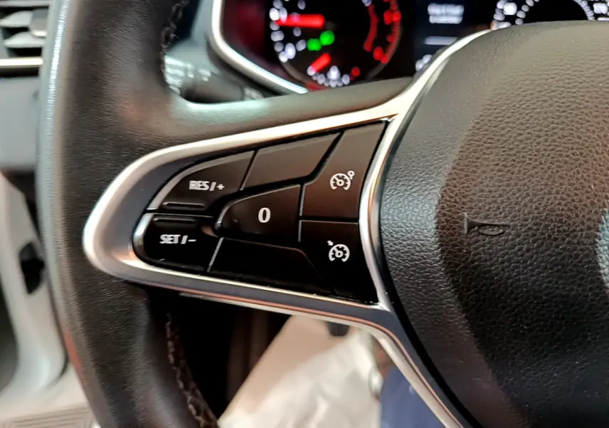 Gros plan sur les commandes du volant côté gauche d'une Renault Clio Business Blue dCi 85, tableau de bord en arrière-plan.