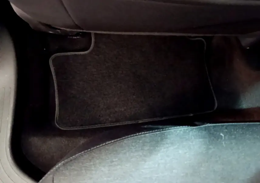 Vue rapprochée du tapis de sol noir côté passager arrière d'une Renault Clio Business Blue dCi 85 blanche de 2020.