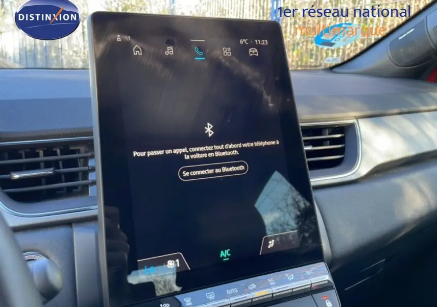 Vue intérieure centrée sur l'écran tactile vertical du tableau de bord du Renault Captur rouge Désir Métal 2025.