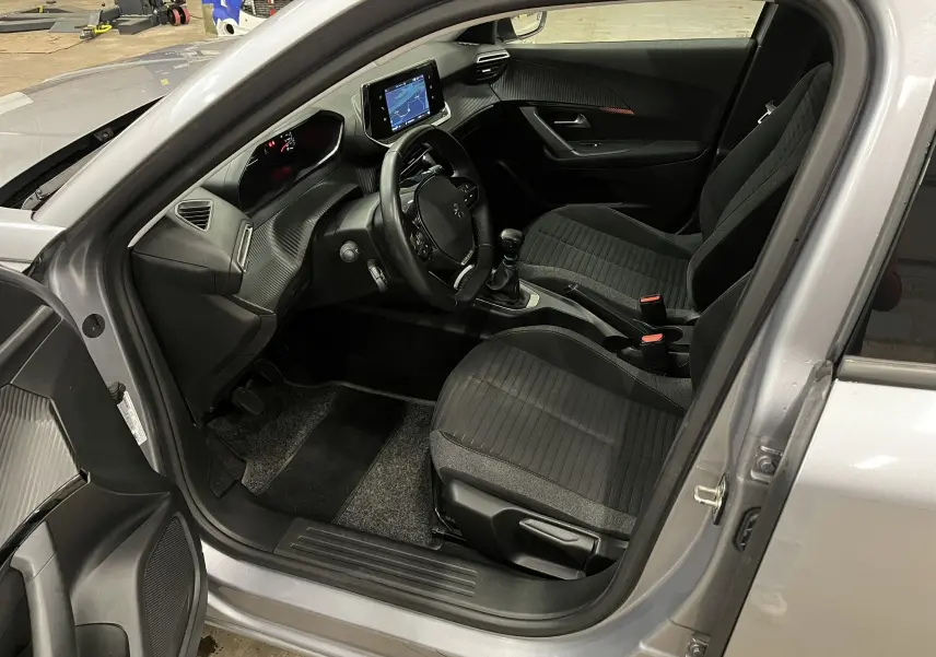 Intérieur avant droit du Peugeot 2008 gris alu 2020, montrant sièges noirs, volant compact et écran tactile central.
