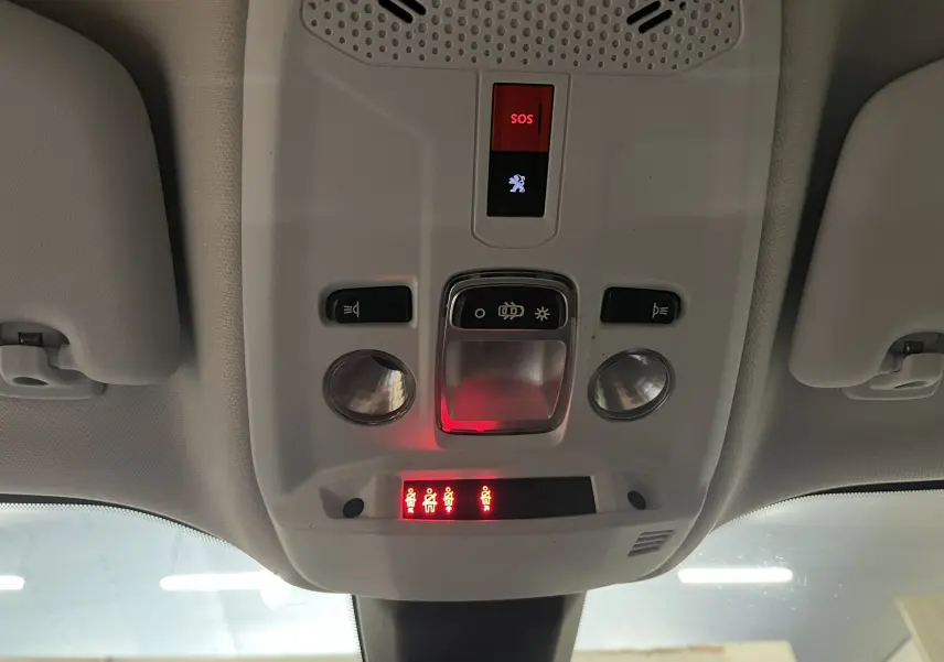 Vue intérieure du plafonnier avant du Peugeot 2008 gris alu, avec boutons SOS et éclairage intérieur allumé.