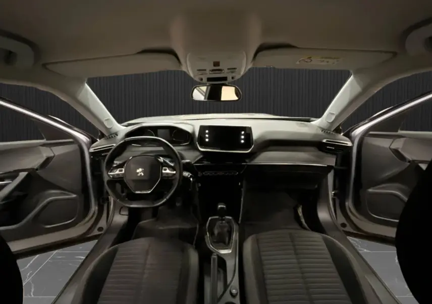Vue intérieure avant du Peugeot 2008 gris alu 2020, tableau de bord moderne avec écran tactile et portes avant ouvertes.
