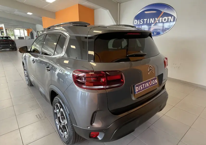 Vue 3/4 arrière d'un Citroën C5 Aircross hybride gris platinium avec vitres surteintées et jantes alliage biton.