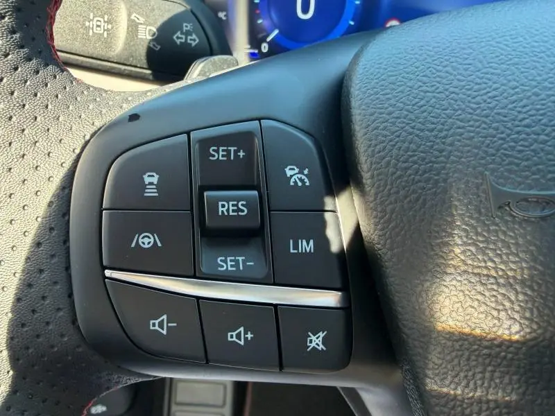 Gros plan sur les commandes multifonctions noires à gauche du volant cuir du Ford Kuga 2024, finition ST-Line.