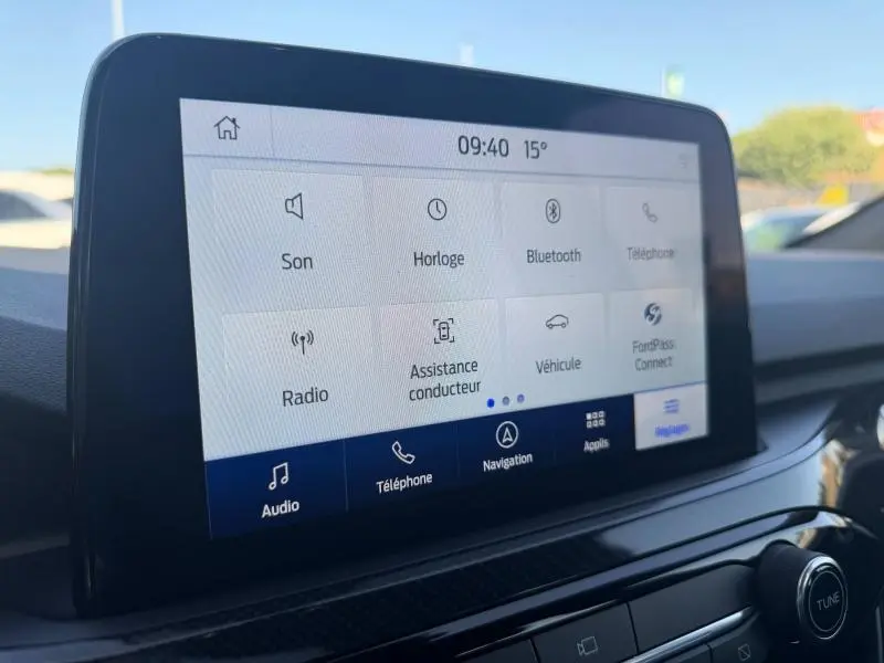 Écran tactile central du Ford Kuga 2024 gris Solar, affichant le menu principal avec options connectivité et navigation.